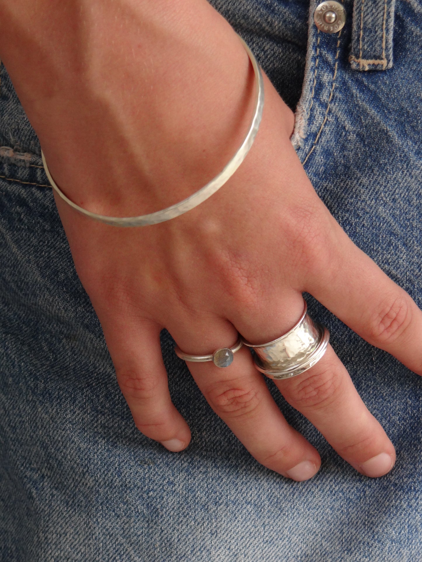 model wearing handmade sterling silver delicate ring with labradorite, handmade sterling silver spinner ring and handmade sterling silver hammered bangle