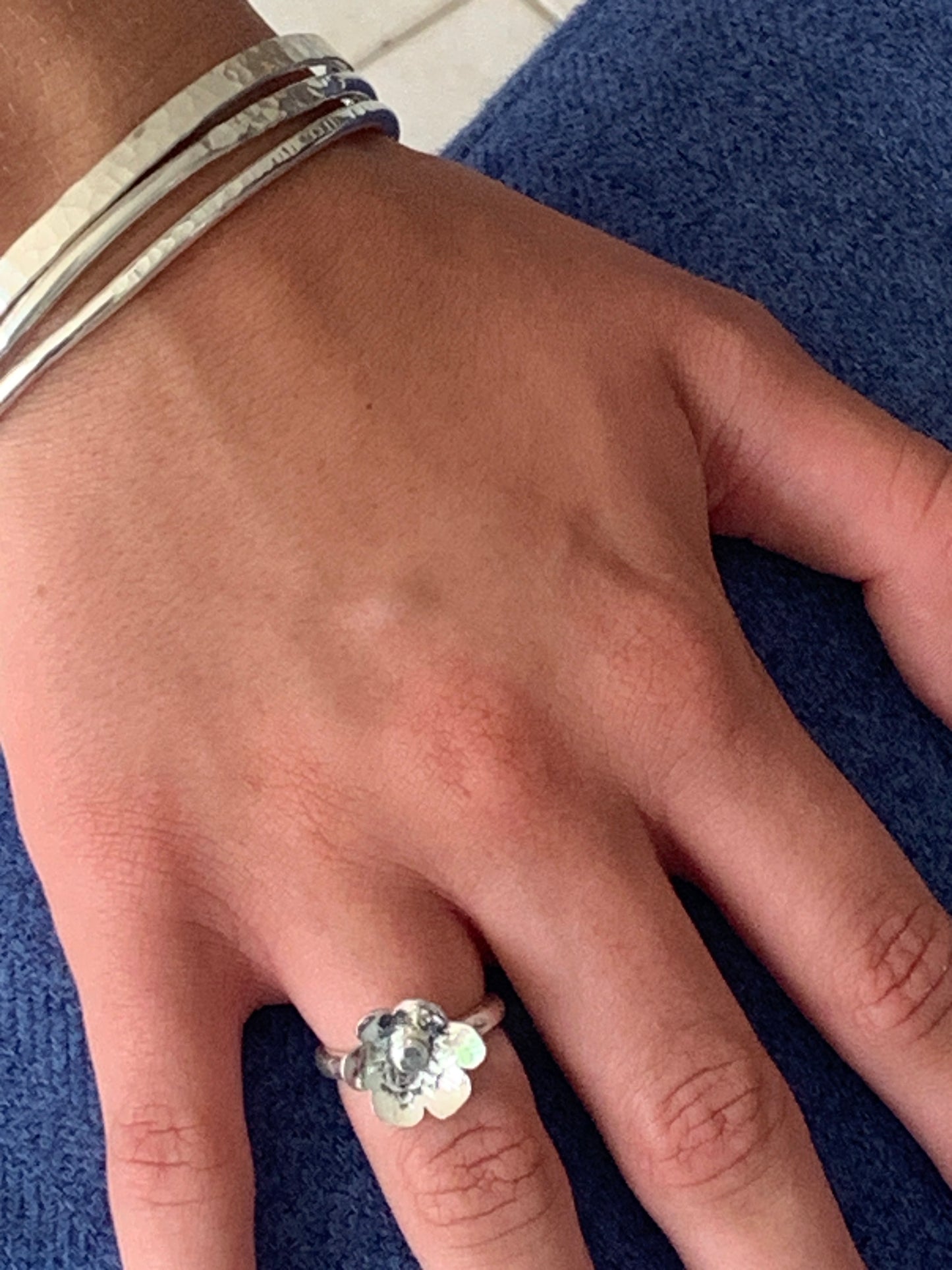 Model wearing handmade sterling silver flower ring and hammered bangles