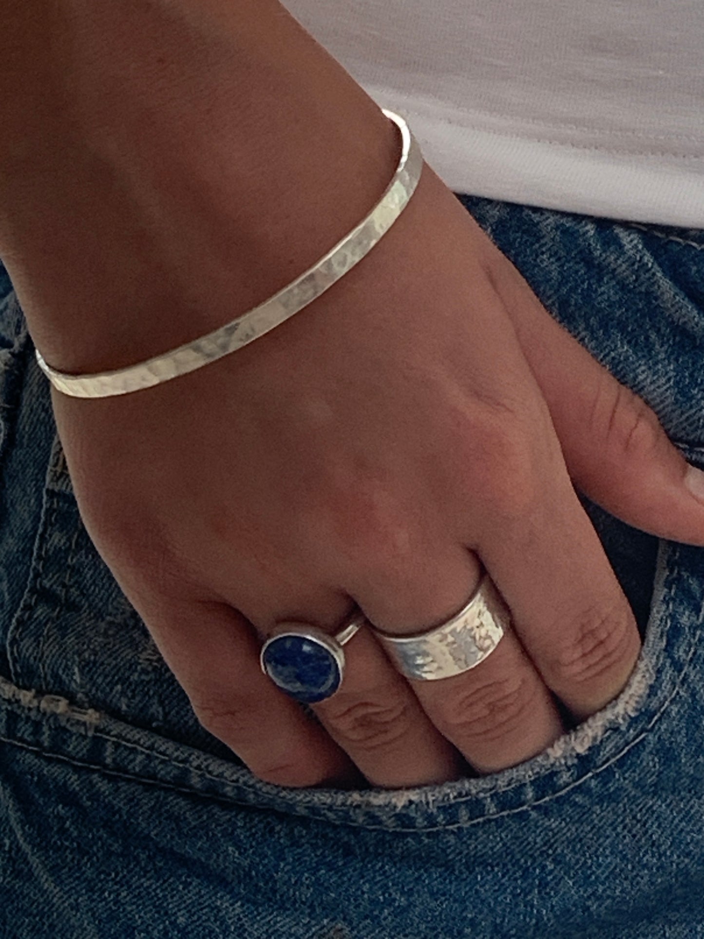 model wearing Handmade sterling silver hammered wide ring, lapis lazuli ring and hammered bangle