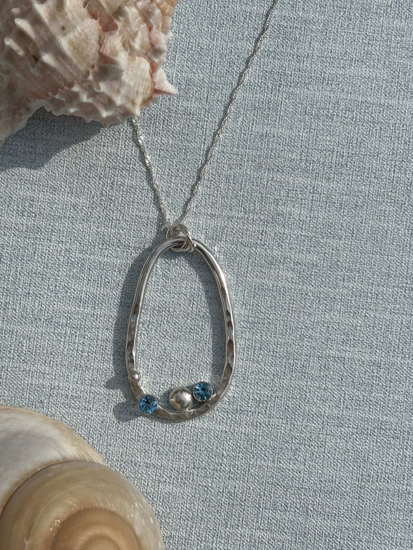 Handmade sterling silver pendant with blue topaz stones and a silver nugget. Hanging on a silver chain.