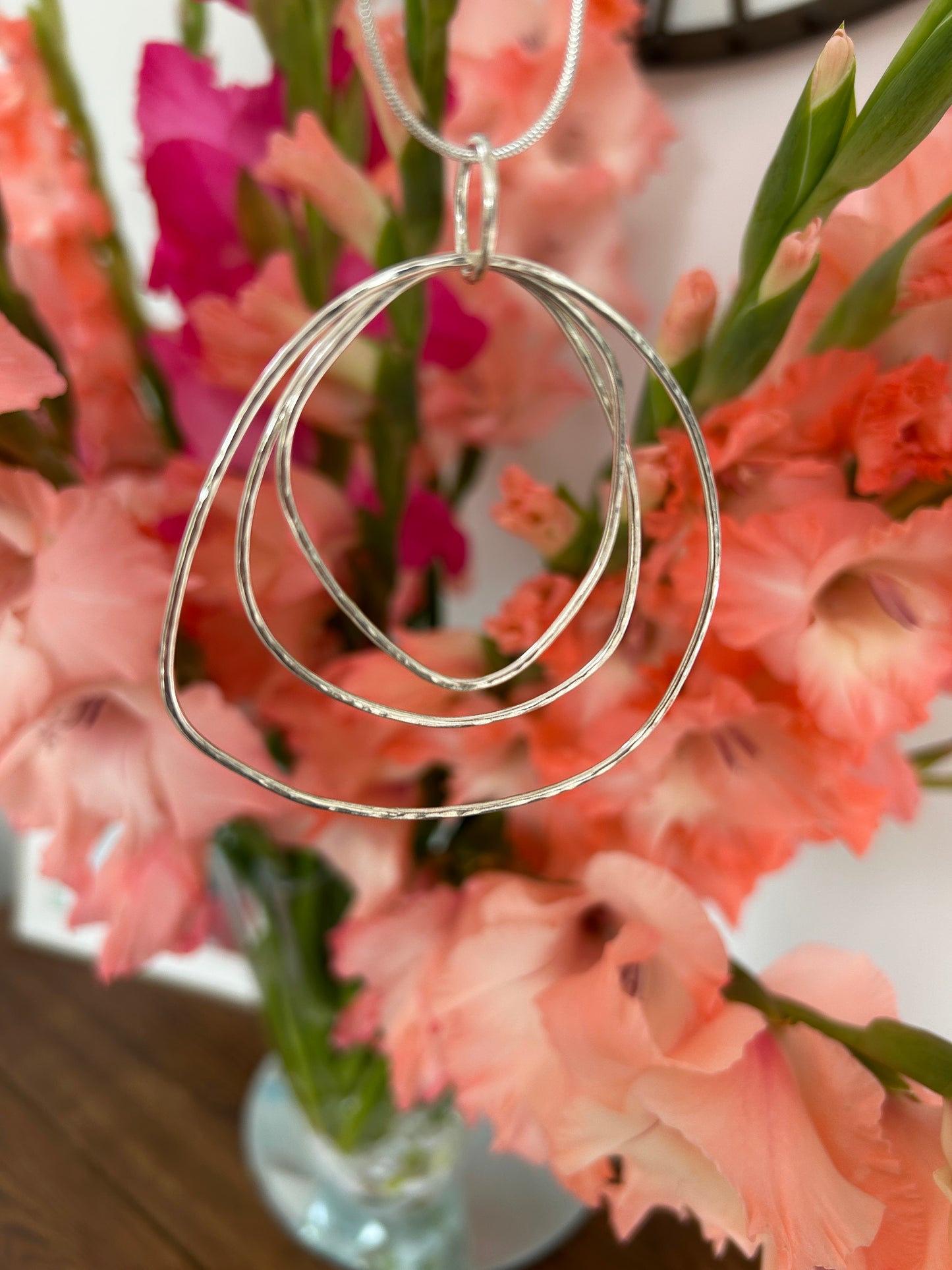 Large pendant made up of numerous circles giving a ripple effect. Hanging on a silver chain.