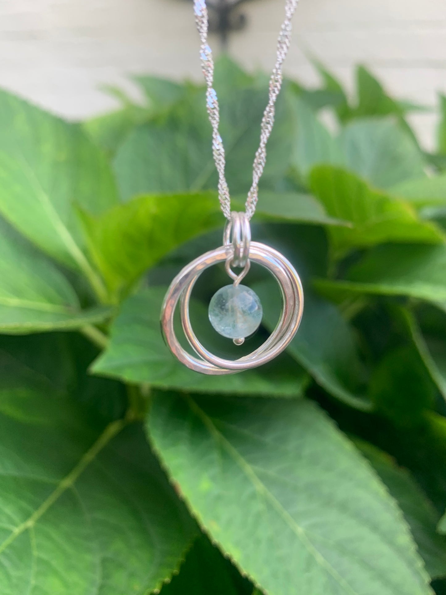 Handmade sterling silver entwined two ring pendant with aquamarine gemstone
