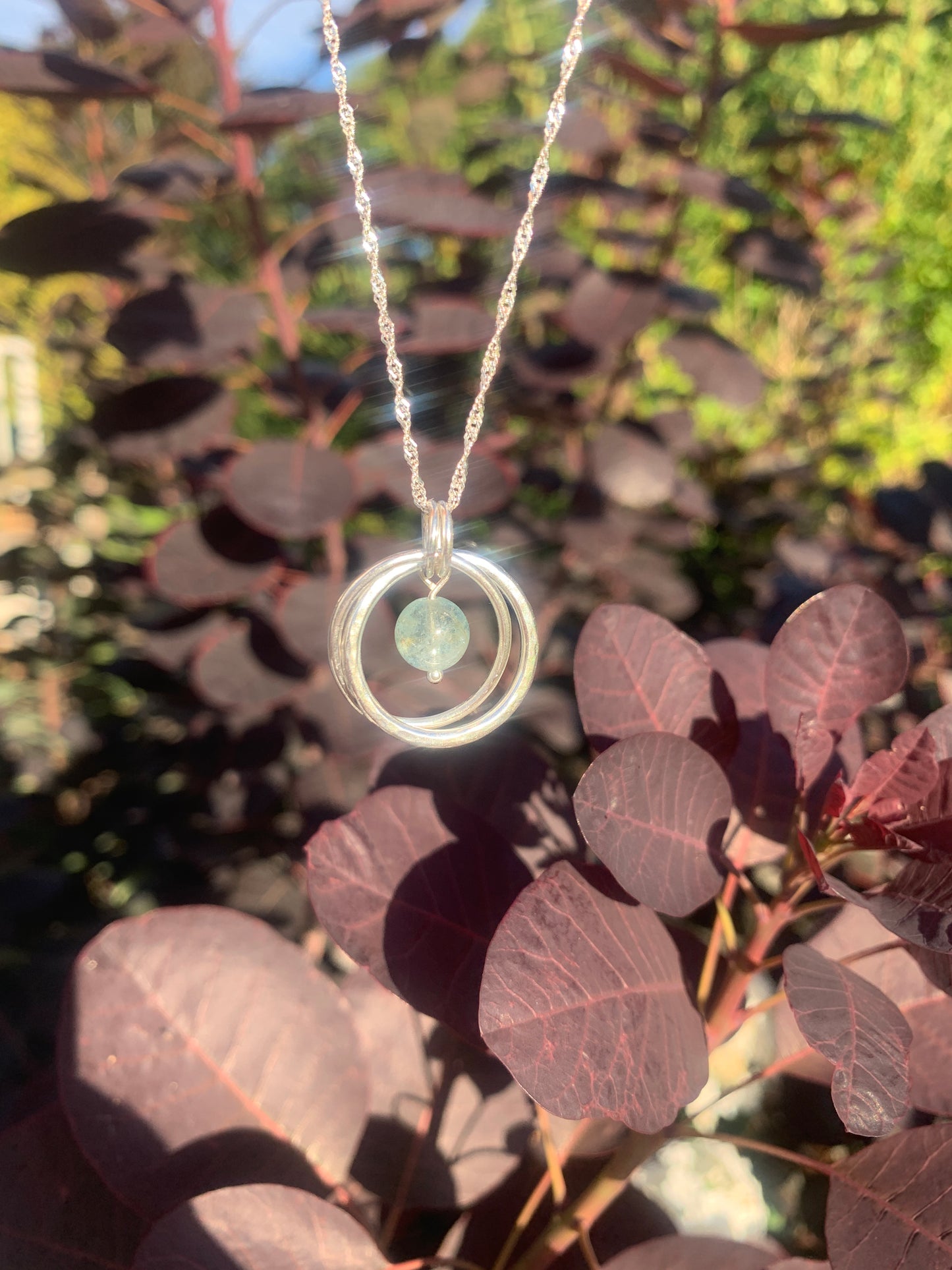 Handmade sterling silver entwined two ring pendant with aquamarine gemstone
