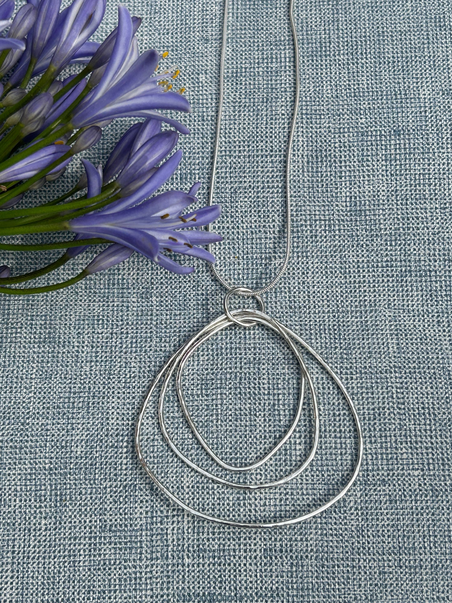 Large ripple handcrafted sterling silver pendant made up of different sizes open shapes hanging on a silver chain