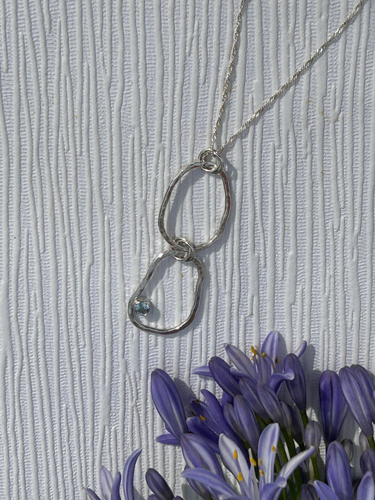Handmade sterling Silver pendant necklace with interlocking rings with blue topaz gemstone hanging on a delicate silver chain.  