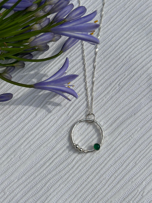 Handmade sterling silver circle pendant with silver nuggets and green onyx gemstone on a silver chain.