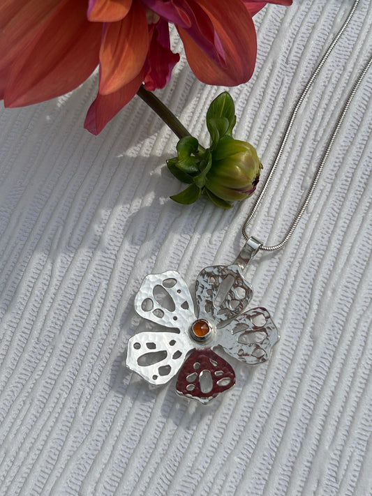 Handcrafted sterling silver floral pendant. Pierced design with a carnelian stone.