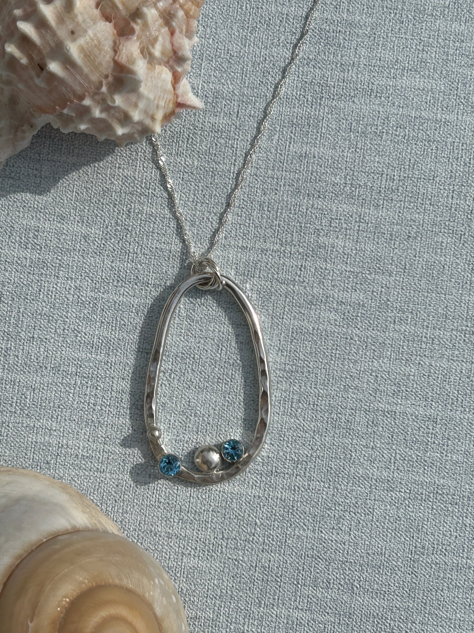 Handmade sterling silver pendant  with blue topaz stones and a silver nugget. Hanging on a silver chain. 