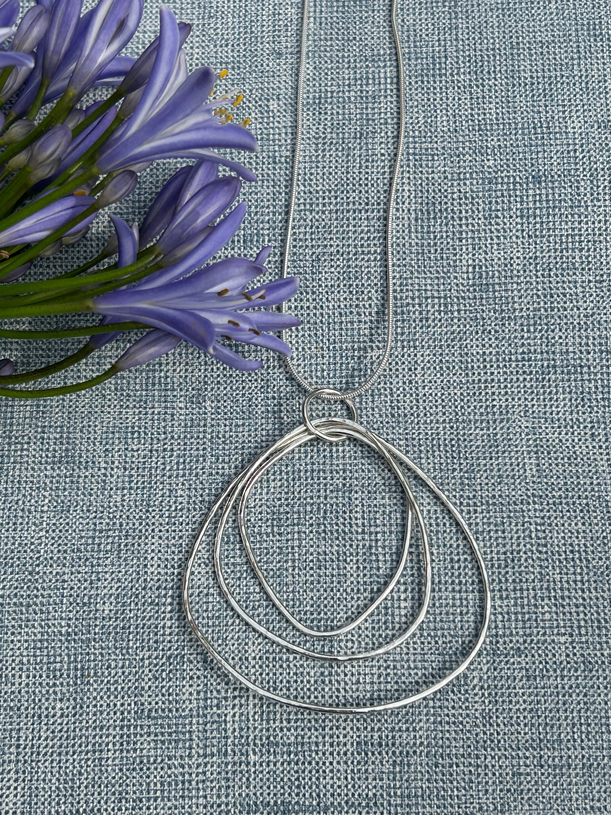 Large ripple handcrafted sterling silver pendant made up of different sizes open shapes hanging on a silver chain