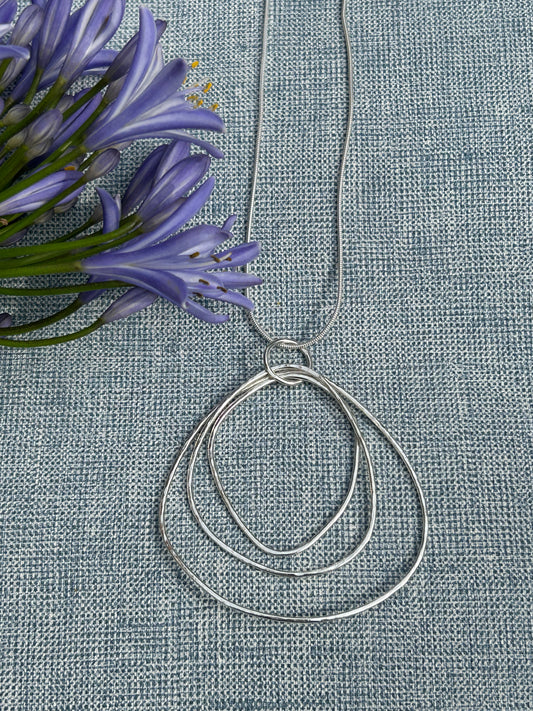 Large ripple handcrafted sterling silver pendant made up of different sizes open shapes hanging on a silver chain