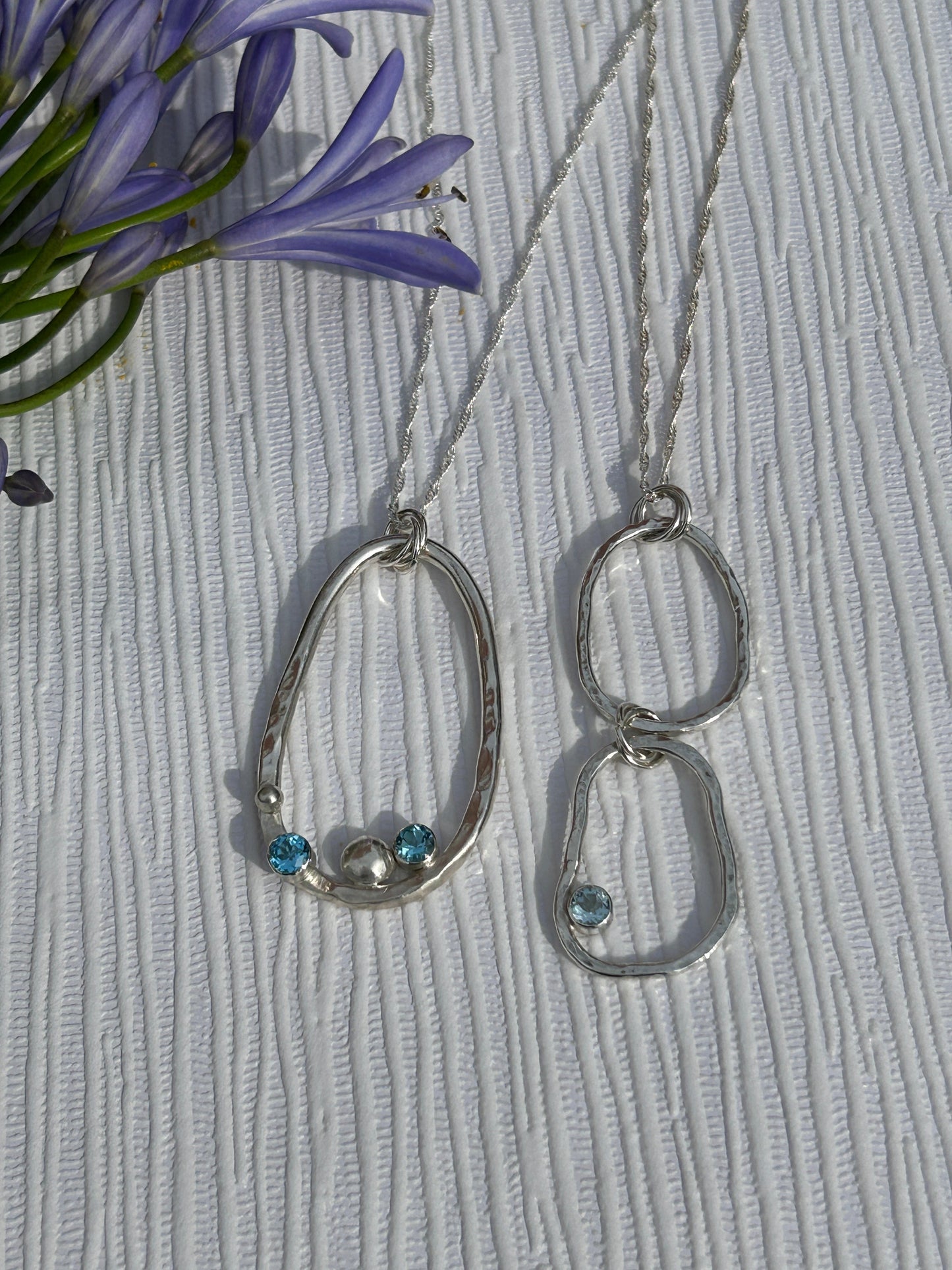 Two handmade sterling silver pendants from the Provence Collection. Hammered finish with blue topaz gemstones
