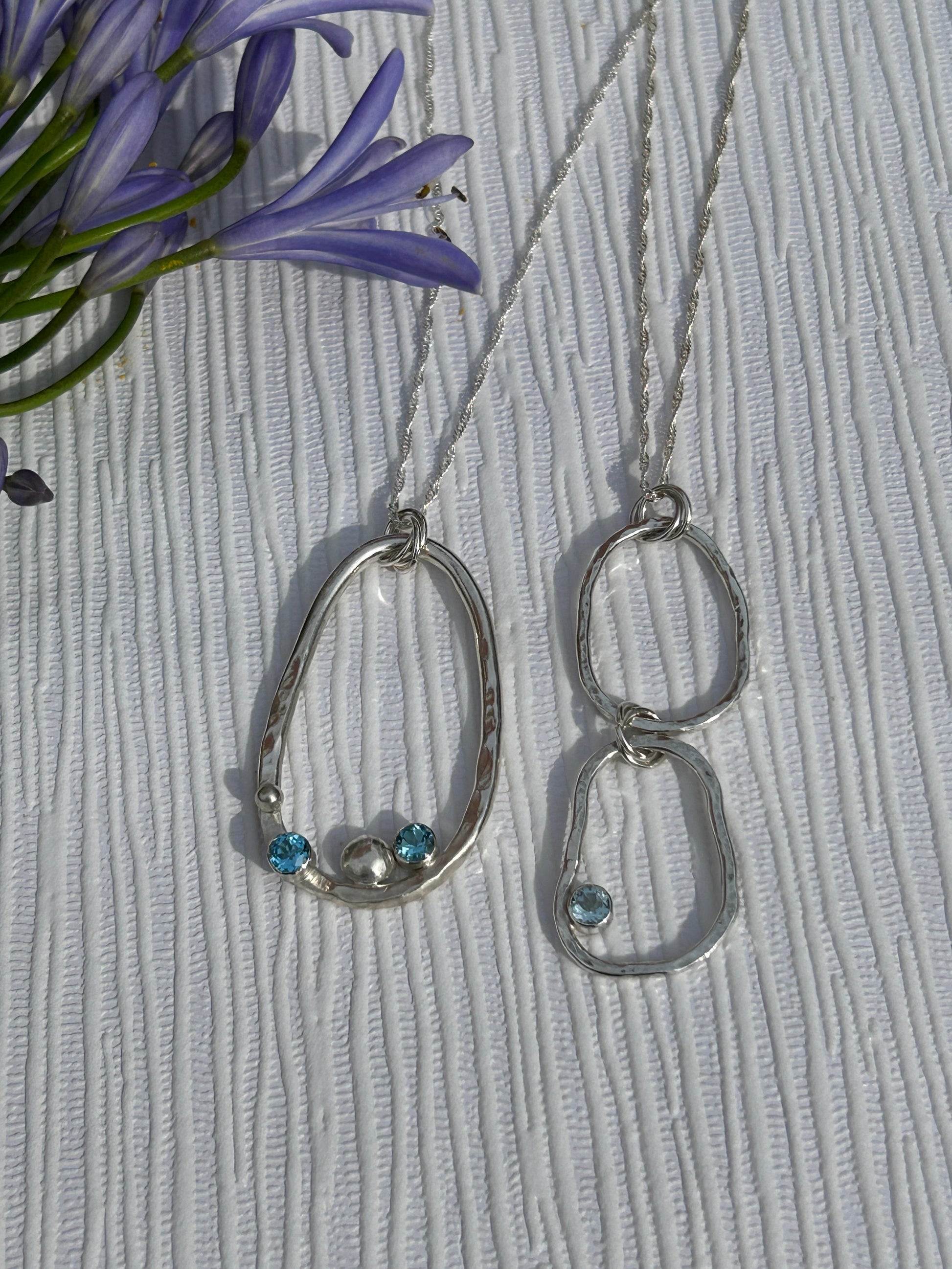 Two handmade sterling silver pendants from the Provence Collection. Hammered finish with blue topaz gemstones